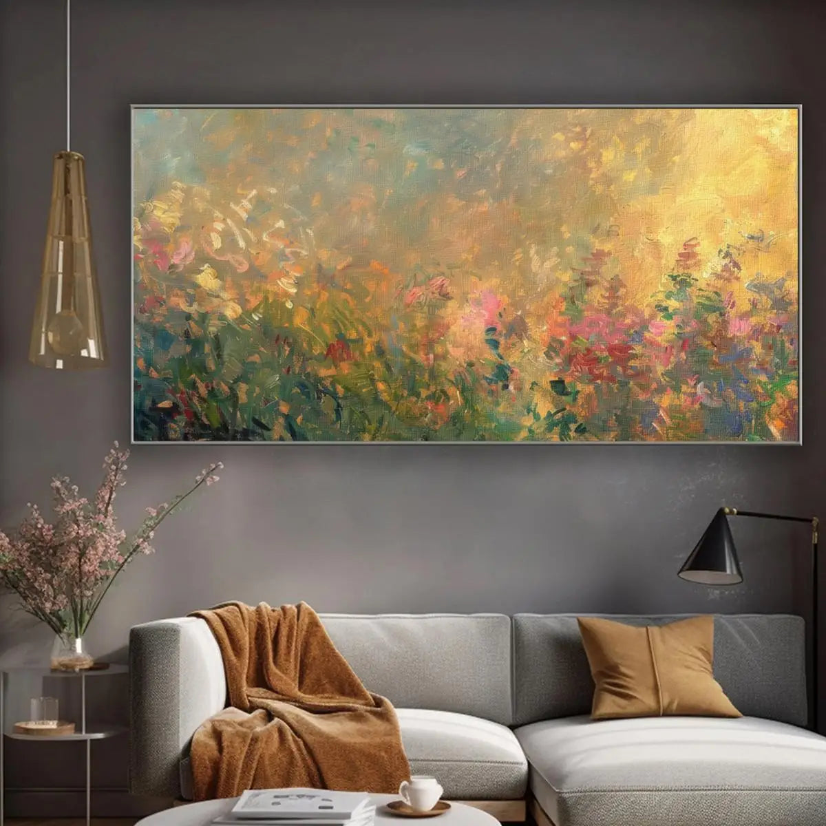 A large rectangular framed wall art piece featuring an impressionistic floral landscape in warm yellow, green, pink, and blue tones, displayed above a light gray sofa in a modern living room setting.